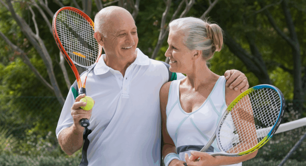 Older couple holding tennis rackets representing personalized wellness and longevity.